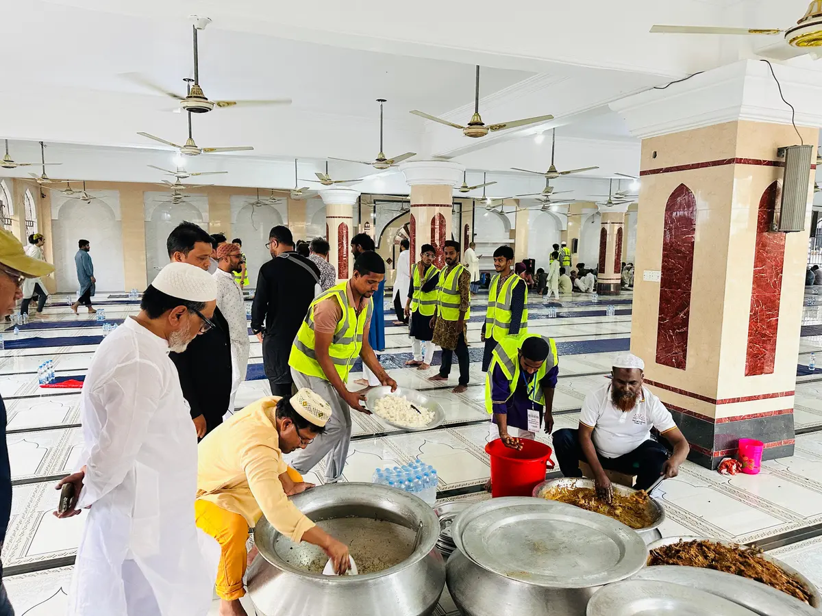 Volunteers in high-visibility vests preparing and serving food at the mosque